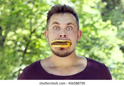 Emotional Young Guy Eating A Cheeseburger On The Nature