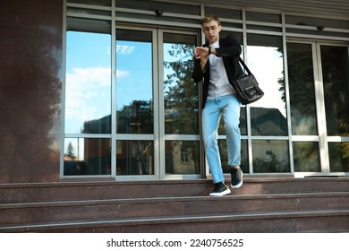 Emotional young man checking time while going down stairs near modern building outdoors. Being late - Shutterstock ID 2240756525