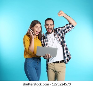 Emotional young people with laptop celebrating victory on color background