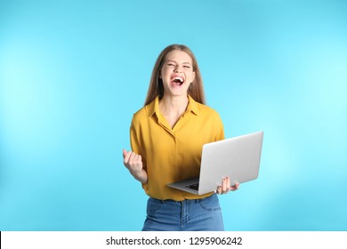 Emotional Young Woman With Laptop Celebrating Victory On Color Background