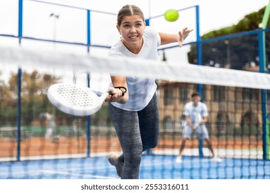 Emotional young woman playing paddle tennis couple match at outdoors court - Powered by Shutterstock