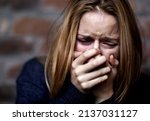 Emotionally victimized. Abused young woman crying hard and covering her mouth.