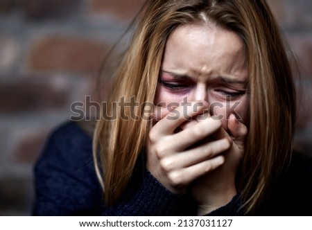Emotionally victimized. Abused young woman crying hard and covering her mouth.