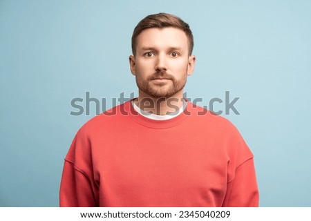 Emotionless middle aged man with serious face expression try calm stands on blue wall studio background. Portrait male sadly looking to camera, thinking about problem, holding back emotions copy space Stock photo © 