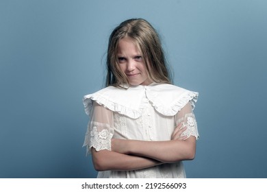 Emotions Of Child. Long Hair Angry Young Girl Looking To The Side. Arms Crossed On Chest. Dark Blue Background.