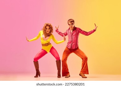 Emotions in movemets. Young stylish emotional man and woman, professional dancers in retro style clothes dancing disco dance over pink-yellow background. 1970s, 1980s fashion, music concept