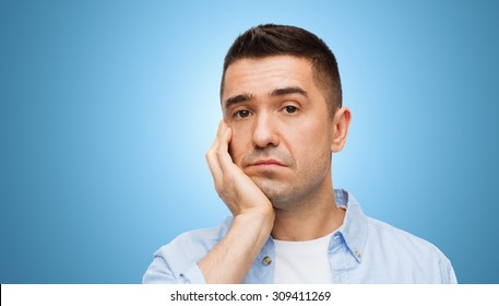 emotions and people concept - bored middle aged man face over blue background