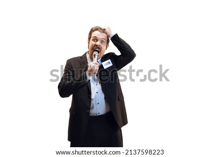 Emotive young man, professional sport commentator, journalist with microphone broadcasting football match isolated over white background. Sport, news, information. Copy space for ad
