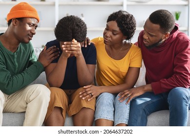 Empathetic millennial black friends supporting crying young lady, embracing and saying good words, group of young men and women sitting on couch at home, having conversation. Friendship concept - Powered by Shutterstock