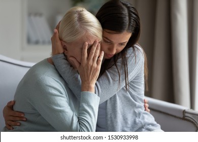  Empathic young lady embracing soothing crying depressed elder mommy, sitting together at home. Upset loving grown up millennial daughter cuddling supporting depressed stressed middle aged mother. - Shutterstock ID 1530933998