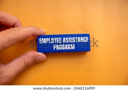 Employee assistance program words written on blue wooden block with orange background. Conceptual employee assistance program symbol. Copy space.