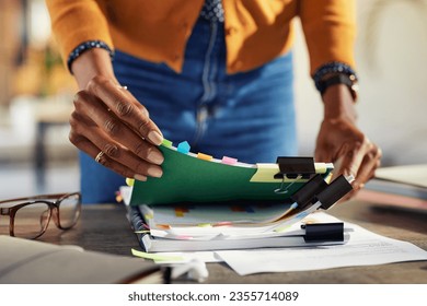 Employee black woman hands working on stacks of workpaper files and searching for unfinished documents. African american secretary holding and arranging stack of business documents and folders. - Powered by Shutterstock