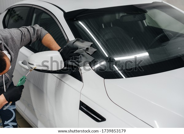 An employee blows and wipes the car after washing.\
Car wash