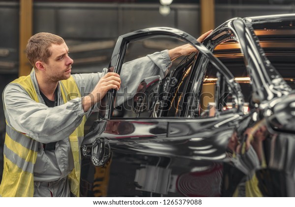 Employee car body painting shop checks the\
quality of the painted\
surface
