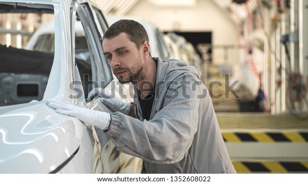 Employee car body painting shop checks the\
quality of the painted\
surface