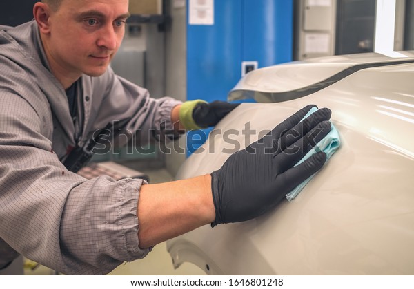 An employee of the car body painting\
shop prepares the element for painting,\
close-up