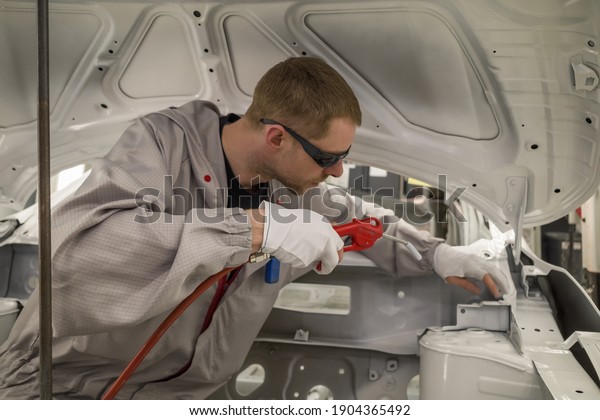 Employee car body painting shop prepares the surface\
for painting, removes\
dust