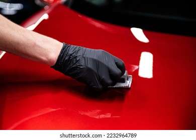 Employee of a car wash or car detailing studio applies a ceramic coating - Shutterstock ID 2232964789