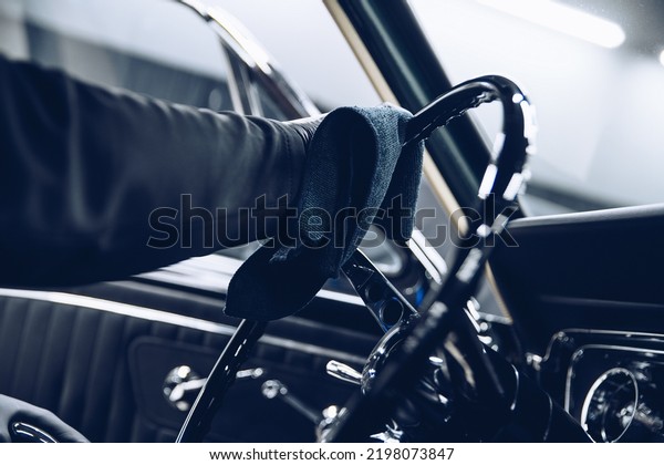 Employee of a car wash or a car detailing studio\
cleans a steering\
wheel