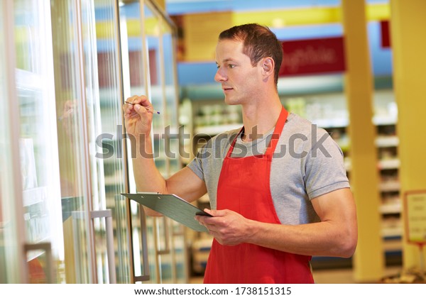 Employee checks inventory in the refrigerated\
section of the\
supermarket