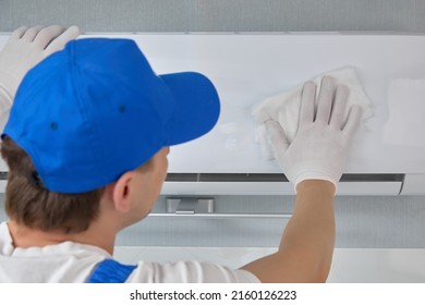 An Employee Cleaning Company Gently Wipes Lid Air Conditioner With Special Napkin With Cleaning Agent. White Cloth Wipes Equipment With An Air Conditioning Technician So That No Fingerprints Are Left