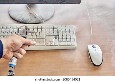 Employee Cleans A Dusty Keyboard And Dusty Desk With Air Duster Cleaning Spray Gun In The Workshop Closeup