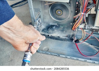 Employee Cleans An Open Old Computer With Air Duster Cleaning Spray Gun In The Workshop Closeup