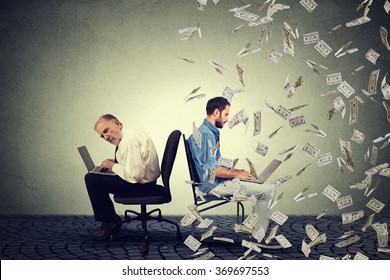 Employee compensation economy concept. Senior man working on laptop sitting next to young entrepreneur guy using computer under money rain. Pay difference concept. 