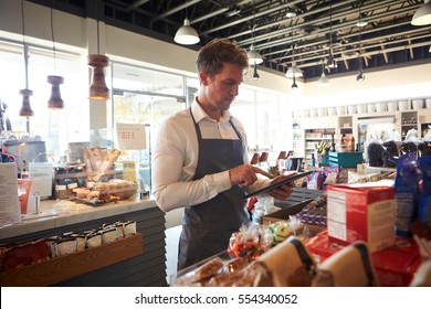 Employee In Delicatessen Checking Stock With Digital Tablet