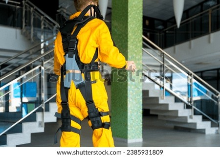 Employee with an exoskeleton from a futuristic high-tech warehouse, stretching to test the suit on his back, help to improve injuries, futuristic physiotherapy, logistics companies