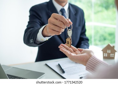 The employee gave the house keys to the customer for mortgage or purchase. Real Estate Agents and Clients Discussing Mortgage Contracts