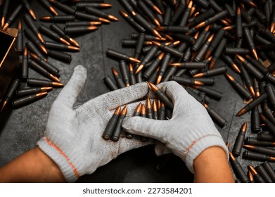 Employee in gloves holds riffle cartridges at workplace