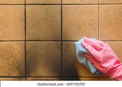 Employee hand in rubber protective glove with rag washing the black soot marks from furnace on tiles wall. Early spring general or regular cleanup. Commercial cleaning company. Service concept.