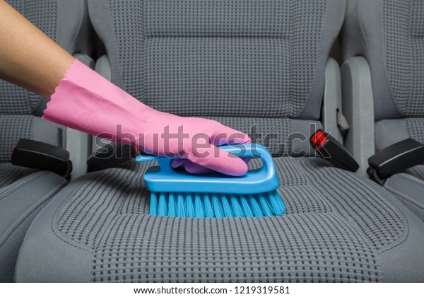 Employee hand in rubber protective glove cleaning\
textile back seat with professionally brush. Early spring regular\
cleanup. Care about auto interior. Commercial cleaning company\
concept. Side view.
