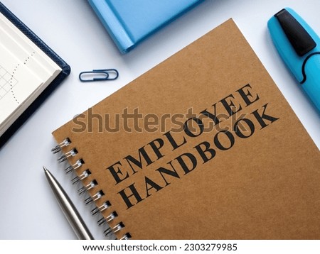 An Employee handbook near notepads and pen.