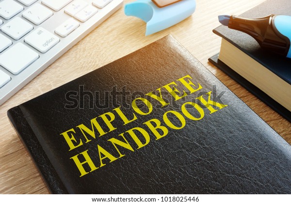 Employee handbook on a wooden\
desk.