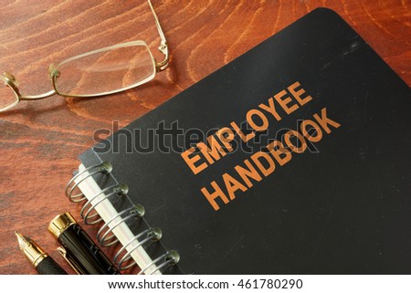 Employee handbook on a wooden table and glasses.
