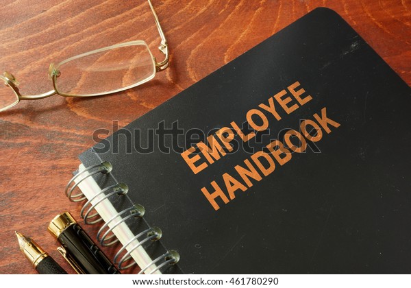 Employee handbook\
on a wooden table and\
glasses.