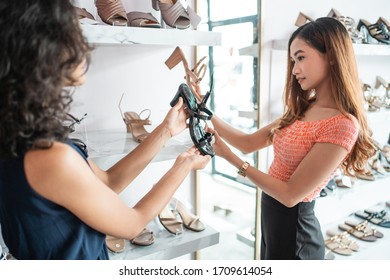 Employee Helping Customer Buying A New Shoes In Fashion Boutique Store