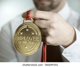 Employee holding golden medal with the text employee of the year. Incentive or motivation concept
