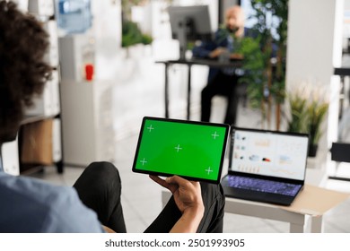 Employee holding tablet with green screen in hand in business office. Start up executive manager using digital device with chroma key display in corporate coworking space - Powered by Shutterstock