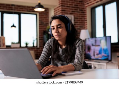 Employee Listening To Music On Headphones And Working On Report With Laptop At Home. Doing Remote Work Job And Enjoying Podcast Or Song, Attending Online Class Webinar On Computer.