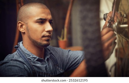 Employee, man and mechanic on bicycle wheel for fixing, repairs or maintenance at workshop. Male person, small business and serious handyman at garage for service, inspection and safety as technician - Powered by Shutterstock