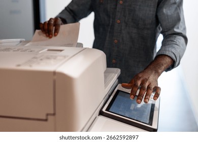Employee operating a multifunction printer, making photocopies and managing various print jobs in a busy office environment