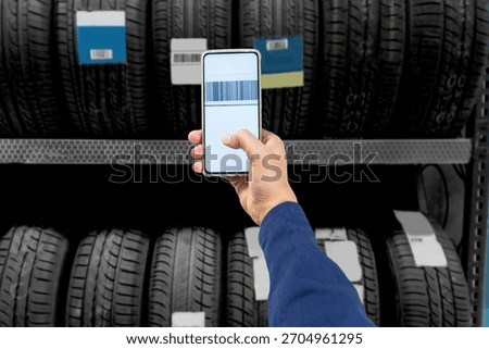 Employee scanning a bar code on a tire at a garage shop using a cell phone.