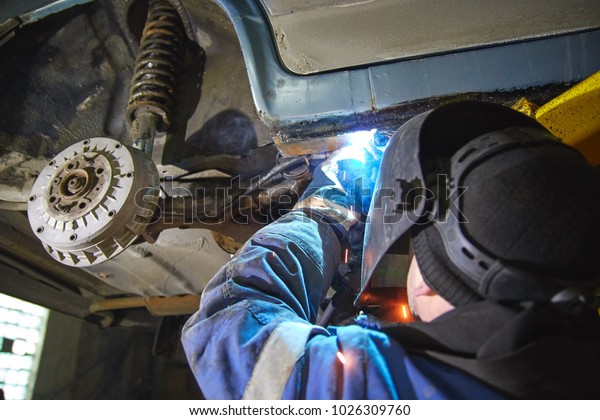 the employee of the service station produces body\
repair with a welding machine in hand. sparks from welding machine.\
car service, car repair