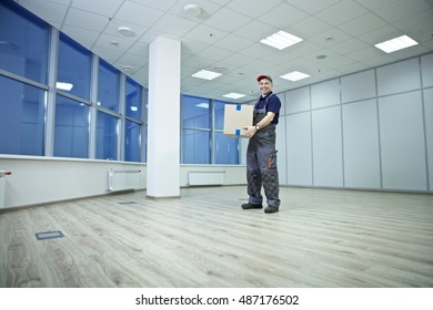 An employee of the shipping service enters into an empty office boxes, packaged items of office furniture. Office with large, bright windows/Moving to New Office