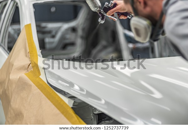 Employee in the shop painting the car body\
produces coloration of the\
element