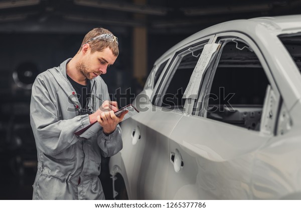 Employee in the shop painting the
car body writes a mark on the defects production defect
maps