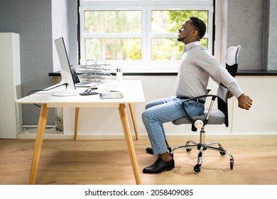 Employee Stretching At Office Desk At Work